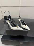Pair of white pointed-toe slingback heels with black lining and gold logo detail.