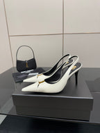 White pointed-toe slingback stiletto heels with black interior and gold logo accent.