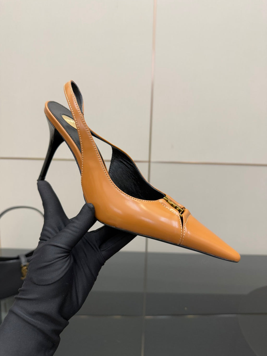 Women’s orange pointed-toe slingback pump in hand with stiletto heel and logo
