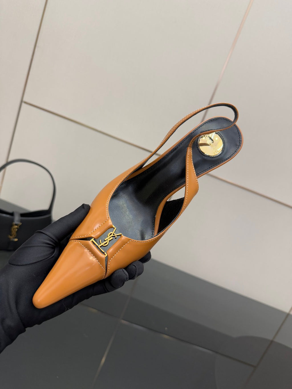 Women’s orange pointed-toe slingback pumps with black interior lining and logo strap