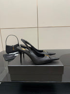 Black slingback stiletto pumps with gold logo detail, angled view on display.