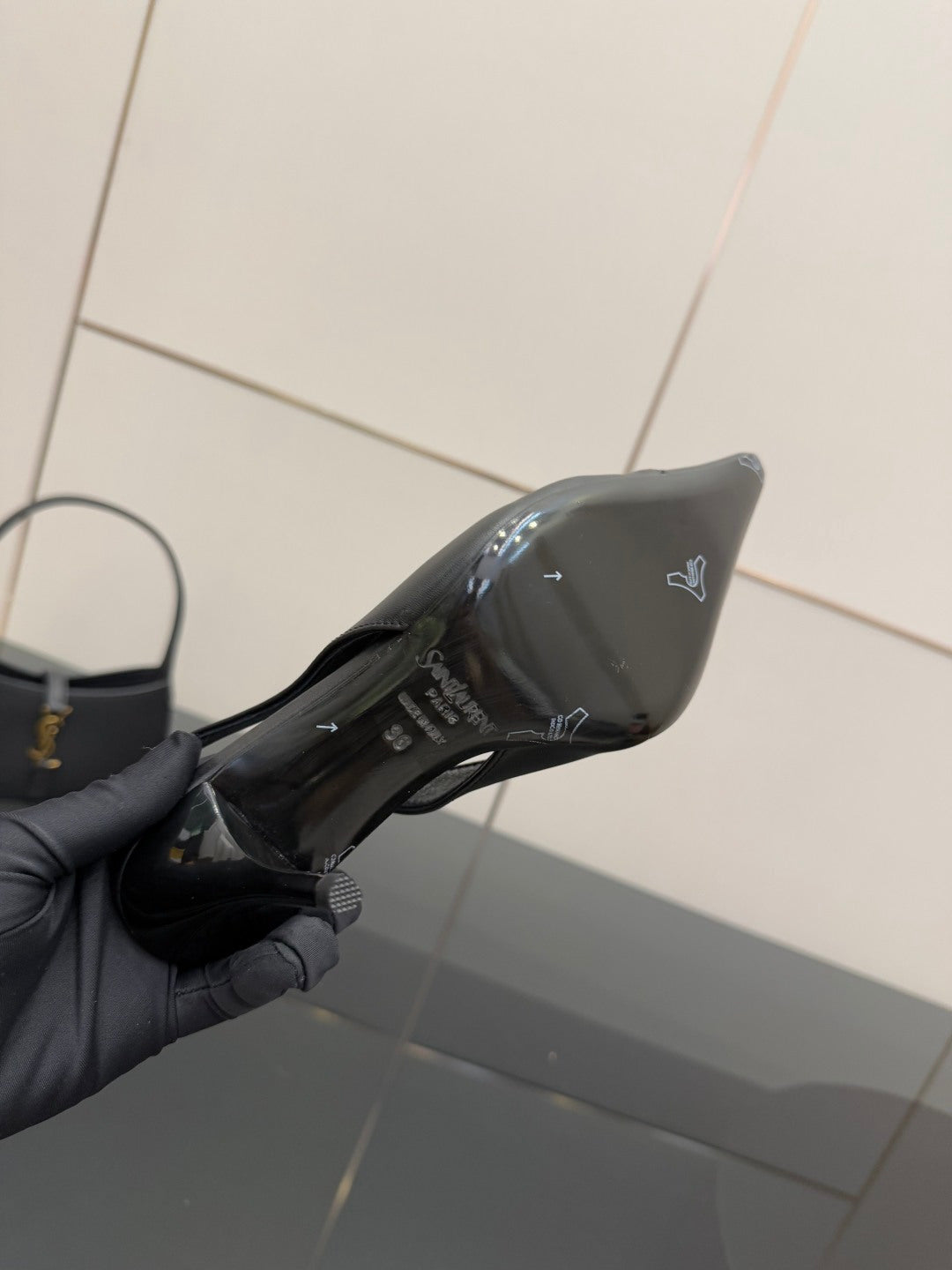 Black pointed-toe stiletto pump interior view, printed lining visible in hand.