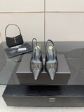 Black pointed-toe stiletto pumps with gold logo detail, on display.
