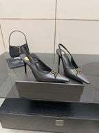 Black pointed-toe stiletto pumps with gold logo detail, front view on display.