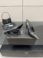 Black pointed-toe stiletto pumps with gold logo trim, heel and toe view on display.