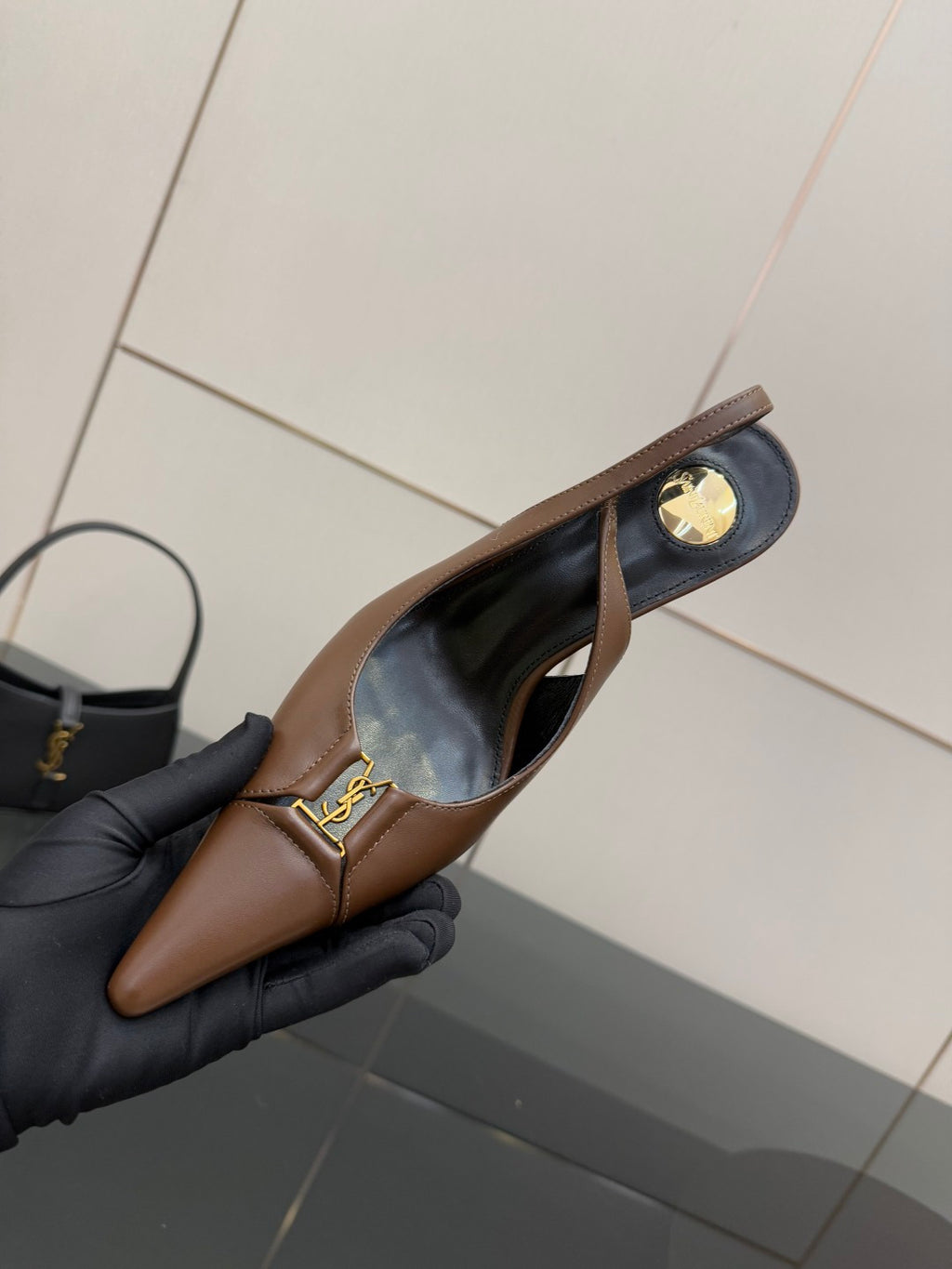 Close view of brown slingback pump with gold-tone buckle and black lining