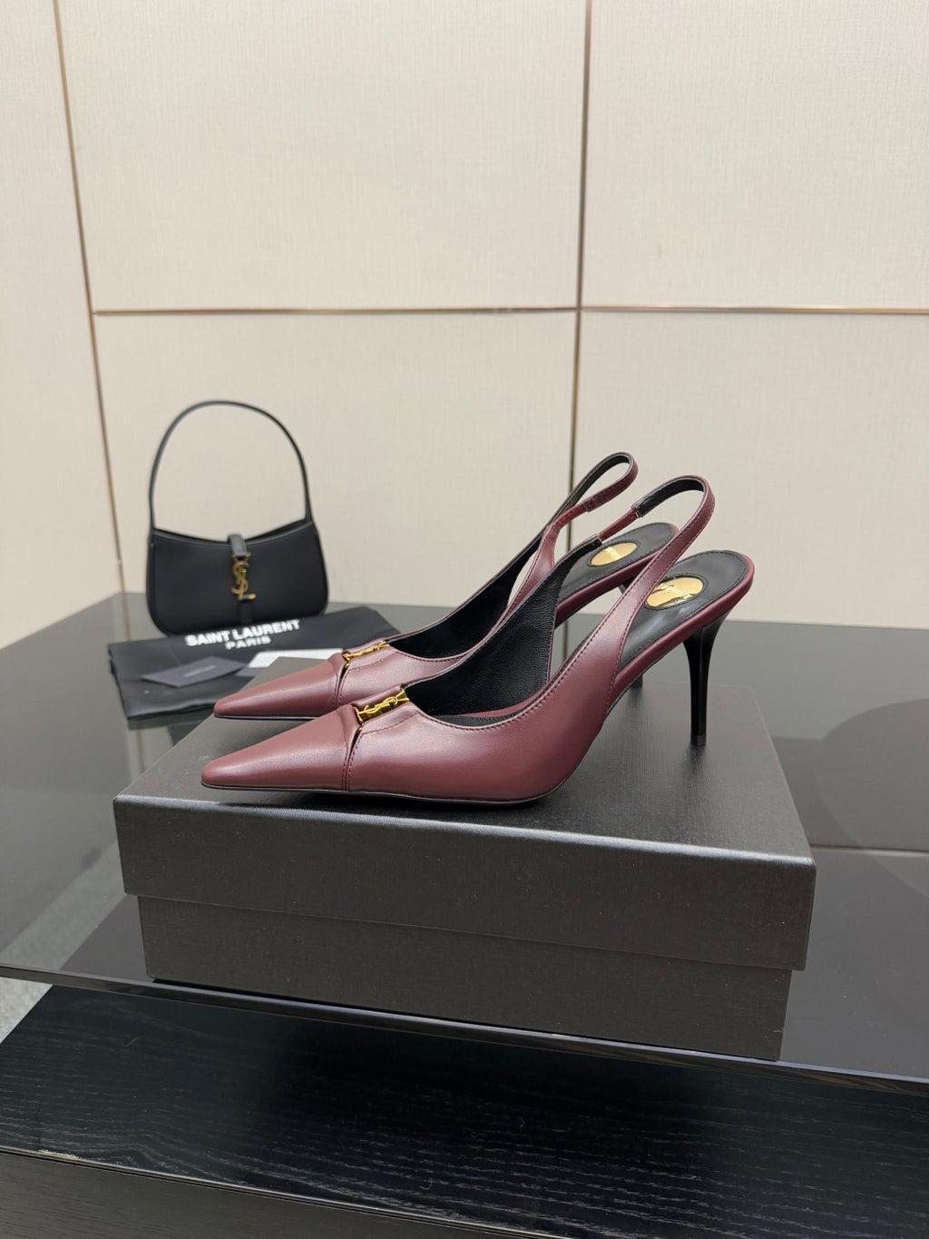 Burgundy pointed-toe slingback high heels on display, gold logo detail