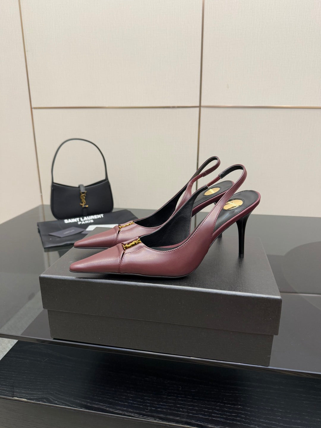 Burgundy pointed-toe slingback high heels on display, gold logo detail