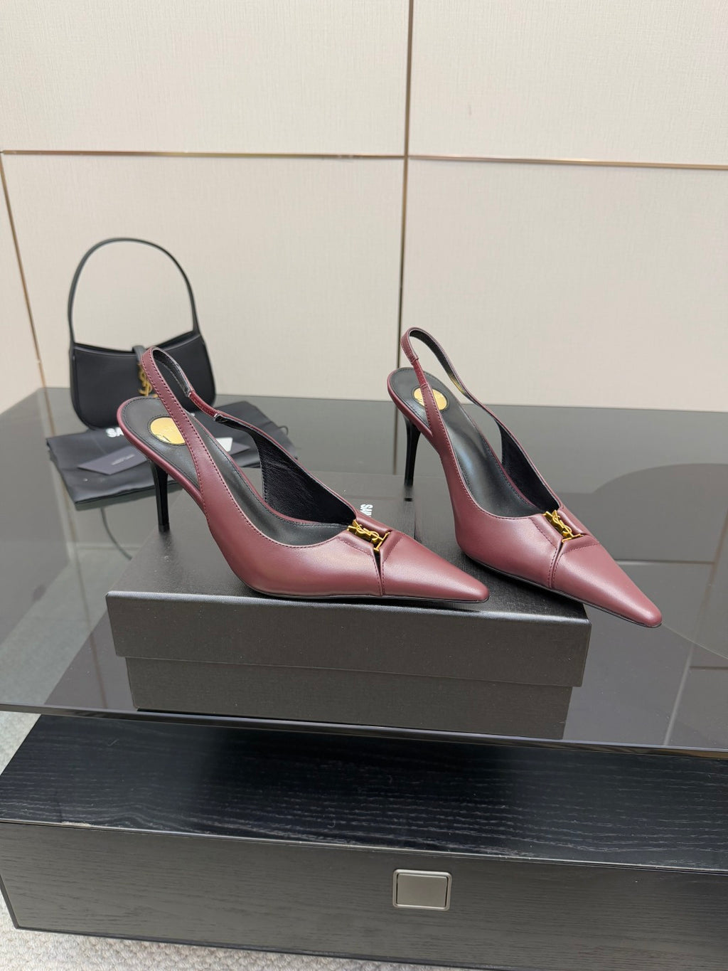 Burgundy pointed-toe slingback heels with gold logo accents, side view
