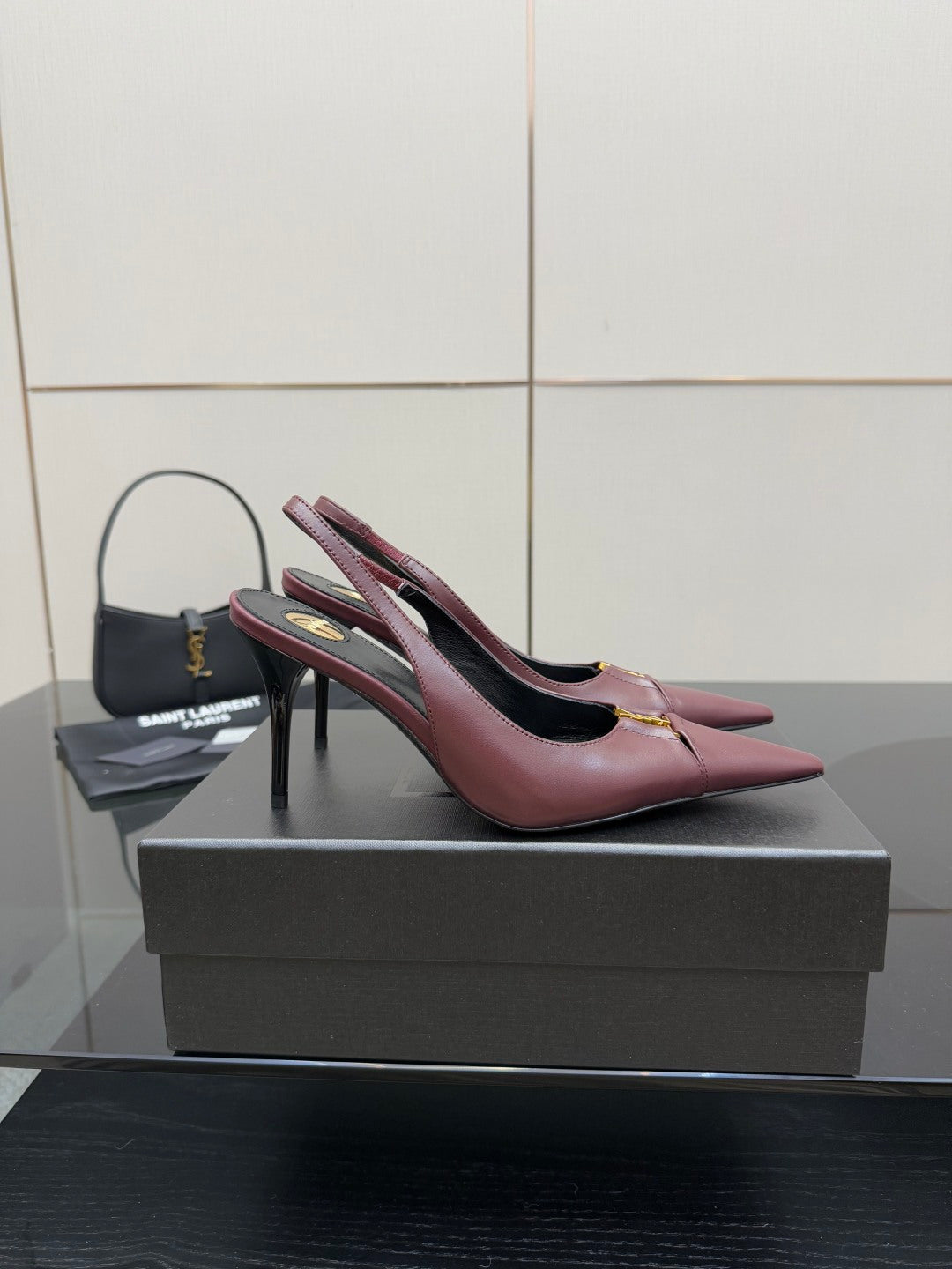 Burgundy pointed-toe slingback heels with gold logo detail, angled view