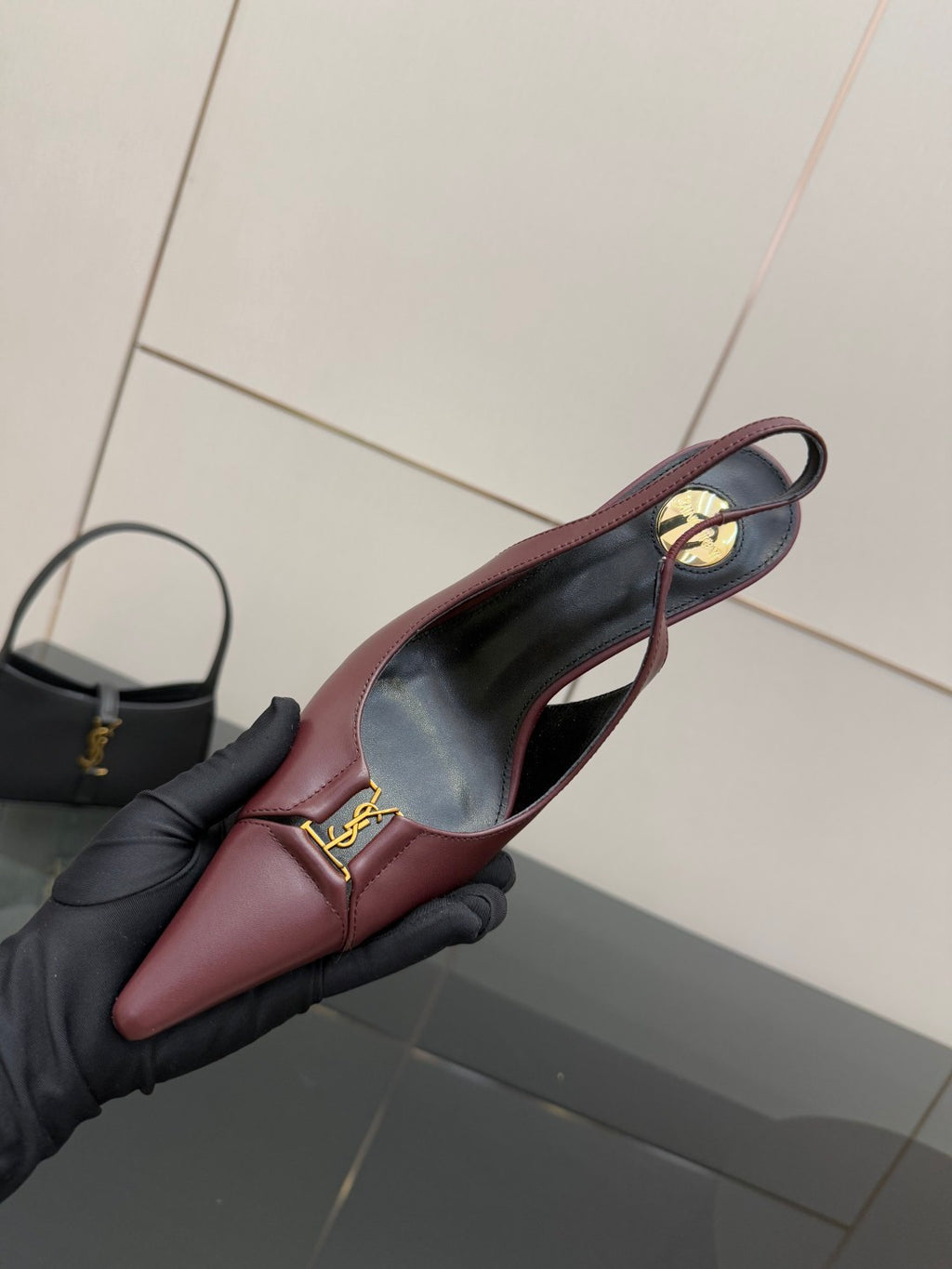 Burgundy pointed-toe slingback heel close-up with gold logo on vamp