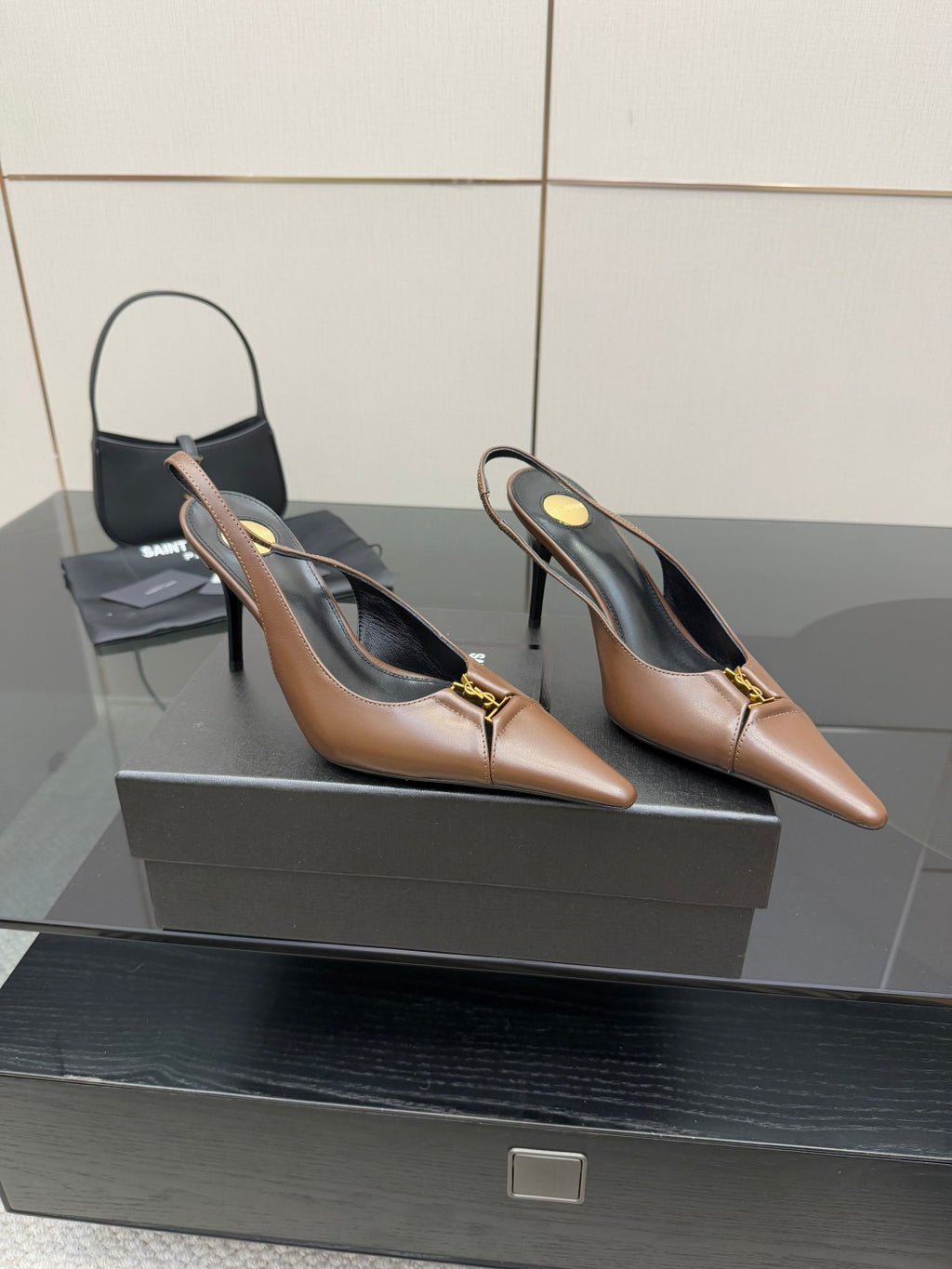 Pair of brown pointed-toe slingback pumps with gold-tone logo detail