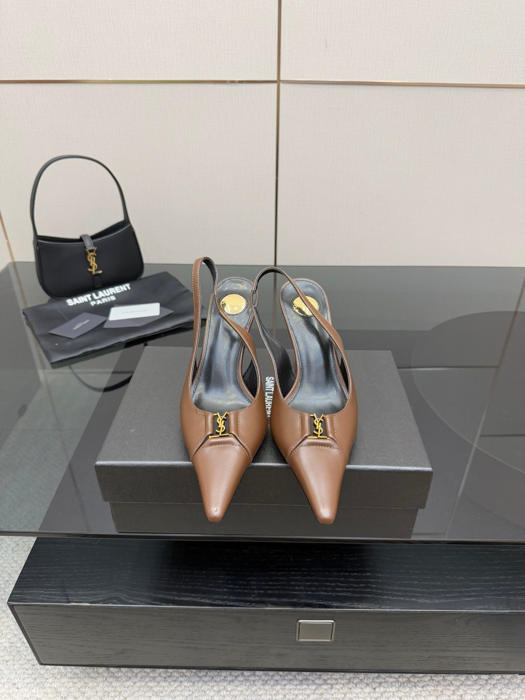 Brown pointed-toe slingback pumps with high heel, shown on a box with matching bag