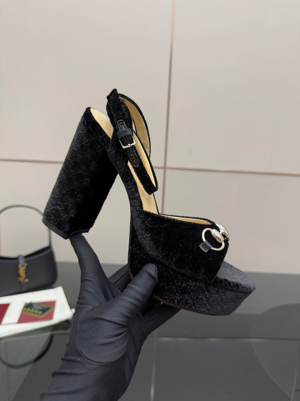 Black velvet platform heeled sandals shown in hand with silver ring strap detail
