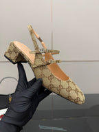 Gucci GG-pattern slingback mule held up, showing crisscross strap with hardware