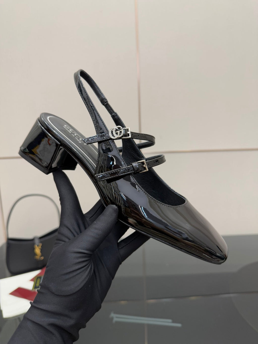 Black patent slingback heel with gold-tone logo buckle and sling strap, pointed toe