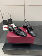 Black patent slingback heels with gold-tone logo buckle, pointed toe, block heel