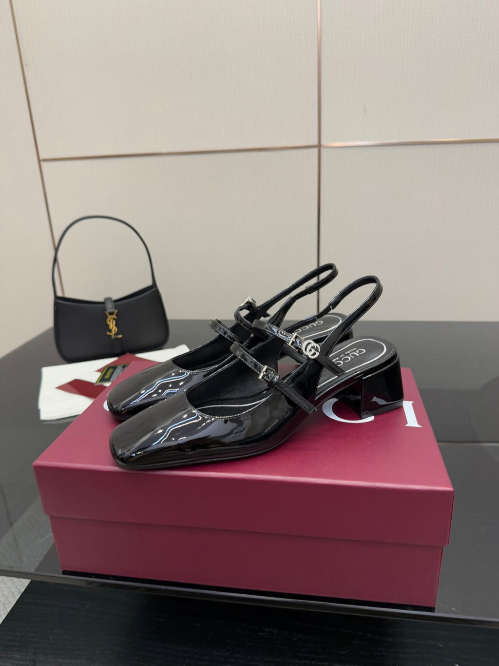 Black patent slingback heels, pointed toe and adjustable buckle strap, on display
