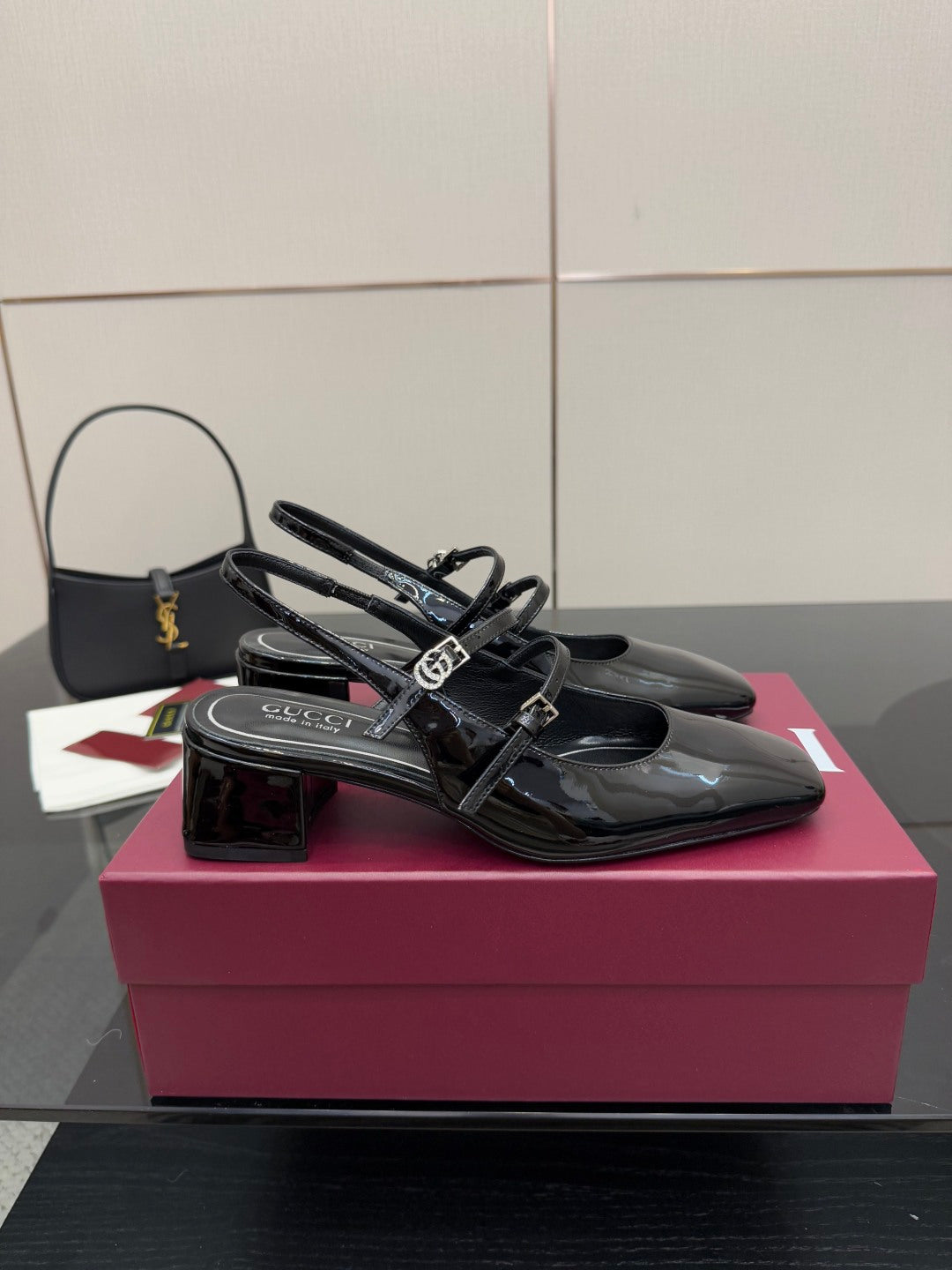 Black patent slingback heels with front strap and logo buckle, block heel