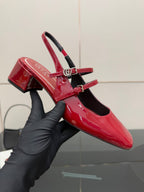 Gucci women’s red patent heels held in hand, chunky block heel detail