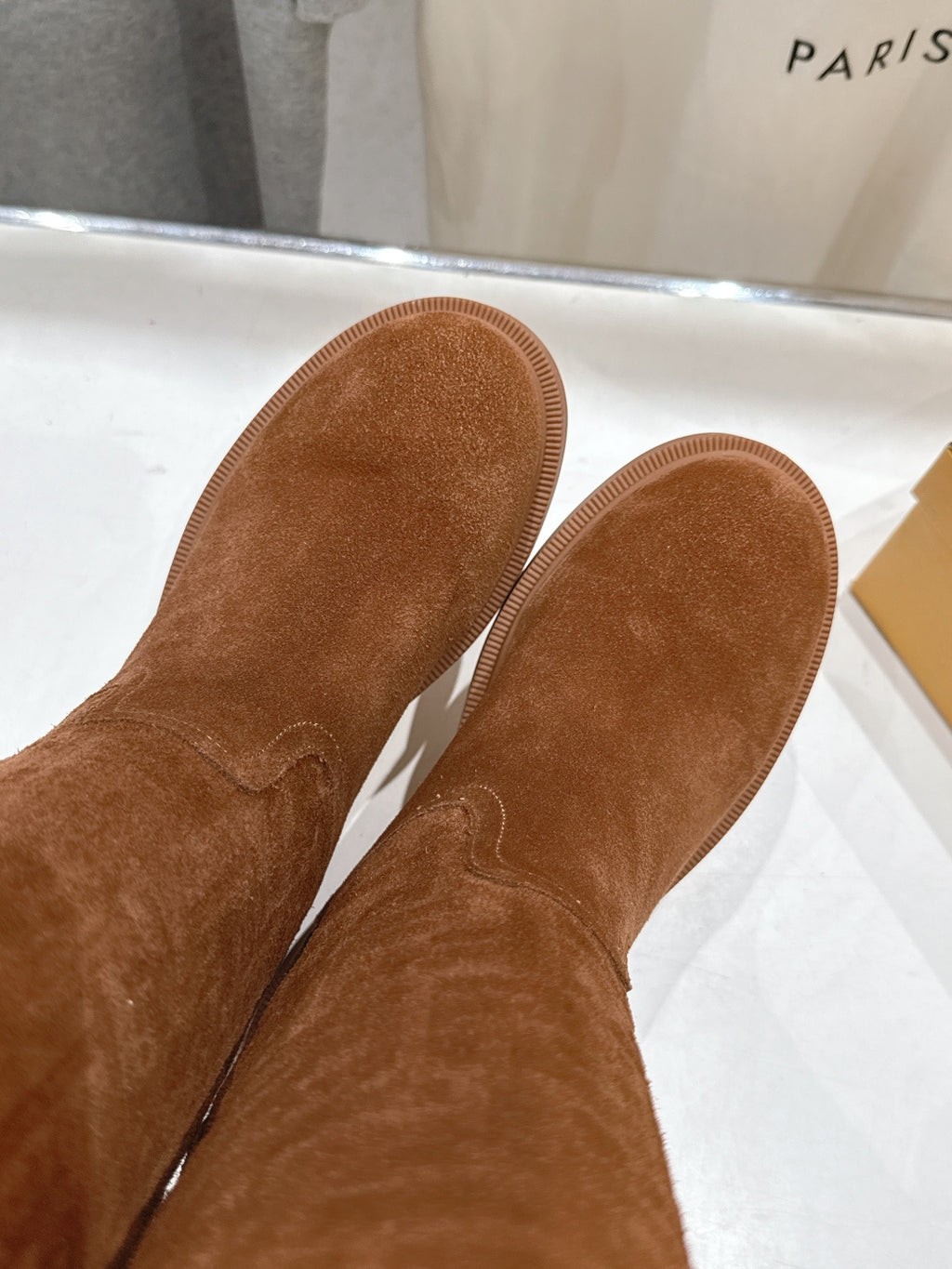 Pair of brown suede boot soles, flat tread underside view