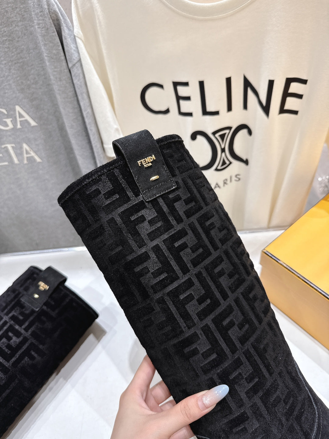 Close-up of black FF-pattern knee-high boot with Fendi logo and gold stud accents