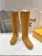Tan knee-high pull-on boots with stitched detail and low flat sole