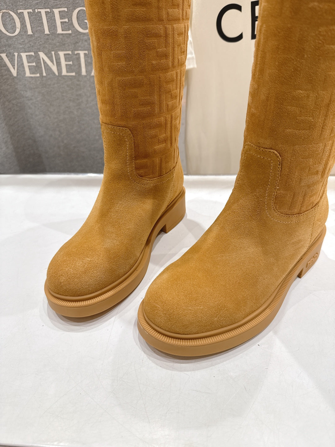 Tan suede knee-high boots front view with stitched seam and flat sole