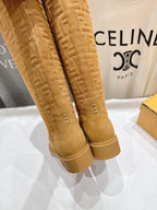 Tan suede knee-high boots close-up, side stitching and stacked rubber sole