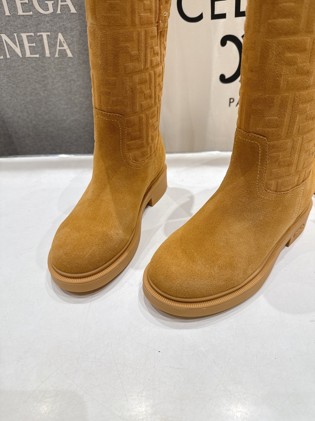 Women’s tan suede knee-high style boots with embossed pattern and low sole
