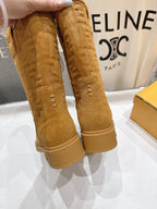 Tan suede ankle boots held by hand, showing stitched seams and pull tabs