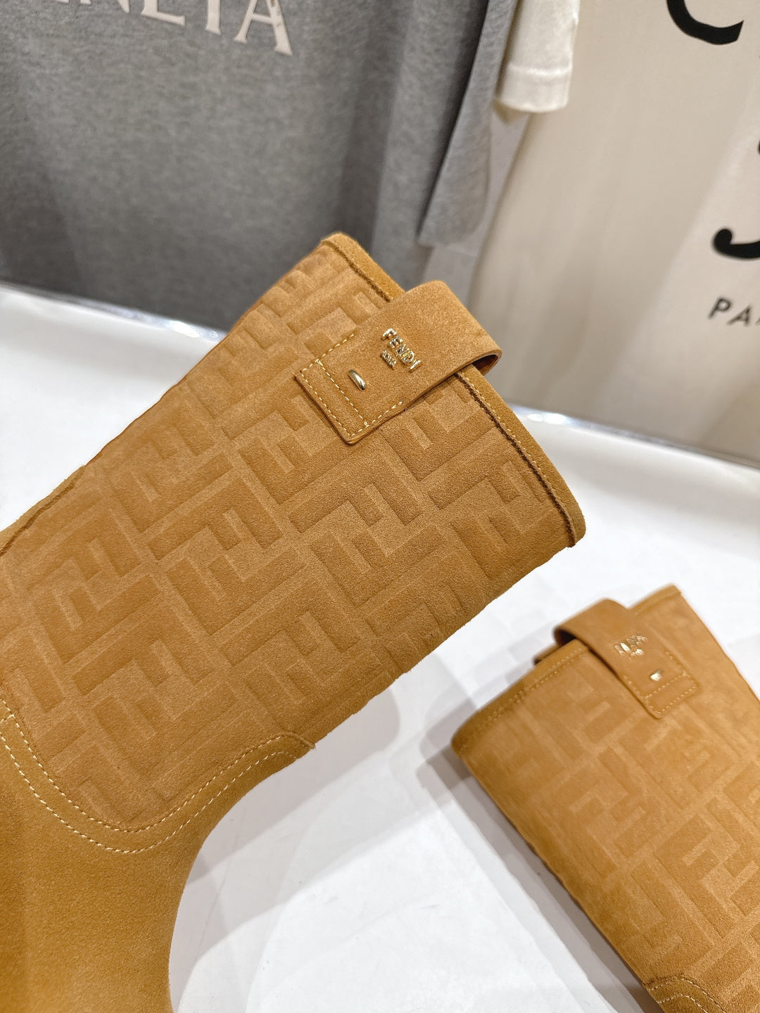 Tan suede ankle boots with embossed monogram pattern and side buckle detail