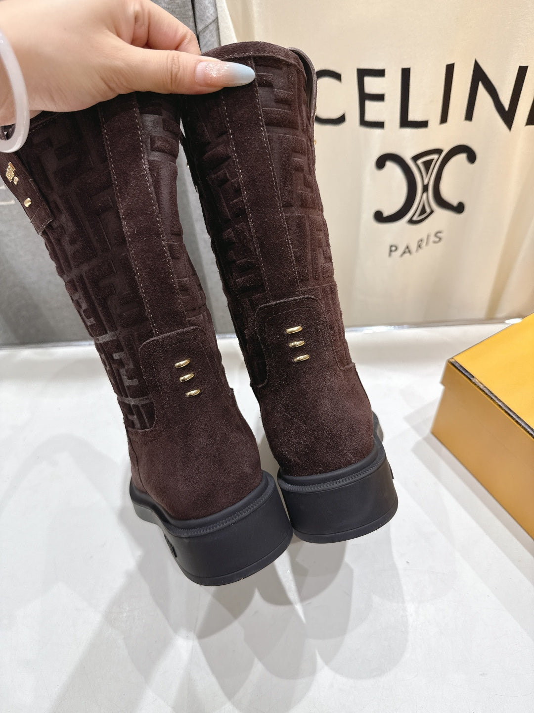 Brown suede tall ankle boots held up, showing embossed Fendi logo
