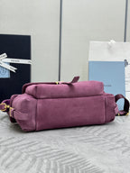 Purple suede handbag with rolled top, stacked straps, and gold-tone hardware accents
