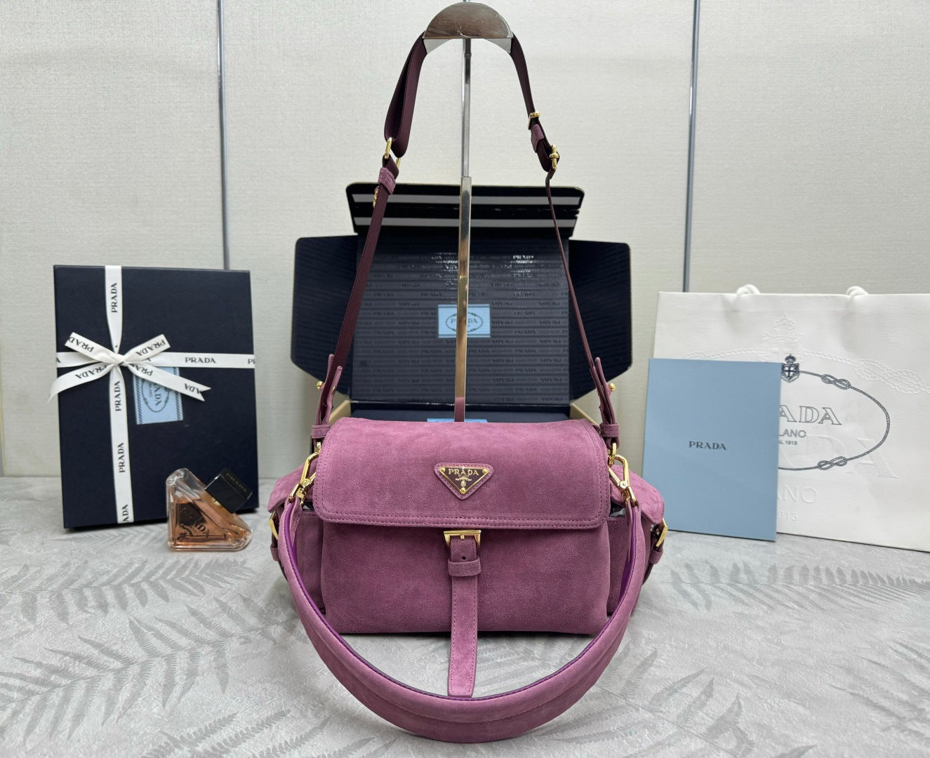 Purple suede shoulder bag with top handle, flap front, and adjustable crossbody strap