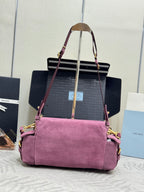 Purple suede handbag with long straps, structured top, and front flap with logo plaque