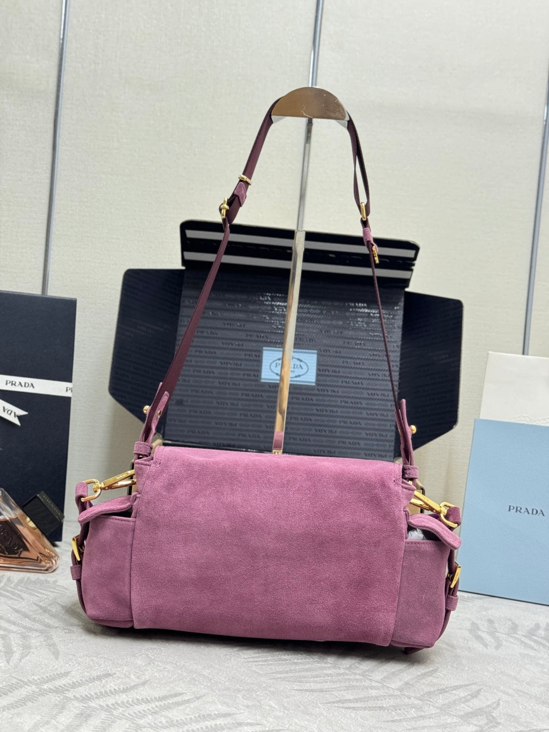 Purple suede handbag with long straps, structured top, and front flap with logo plaque