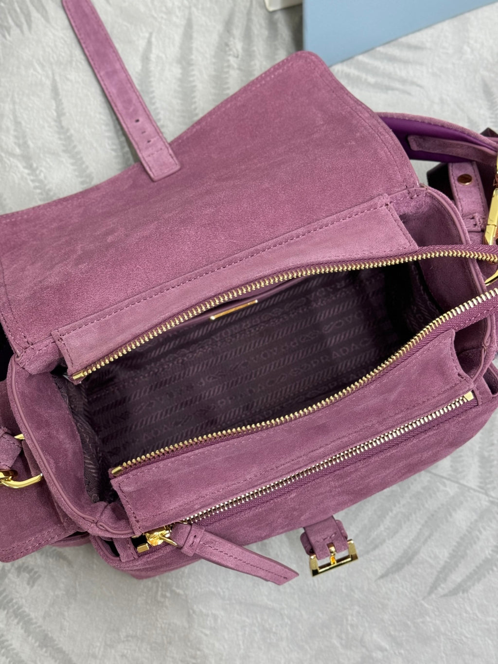 Purple suede bag showing interior lined pocket with gold-tone zipper and hardware