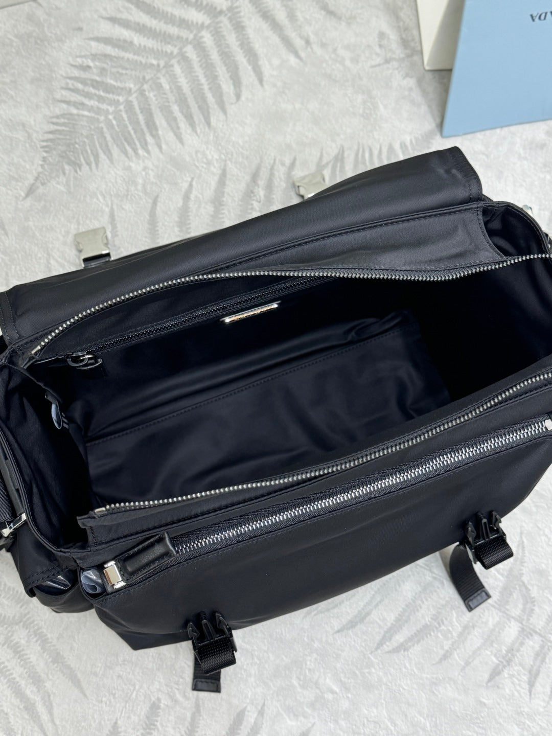 Black Prada nylon bag showing front zipper compartments and silver zipper pulls