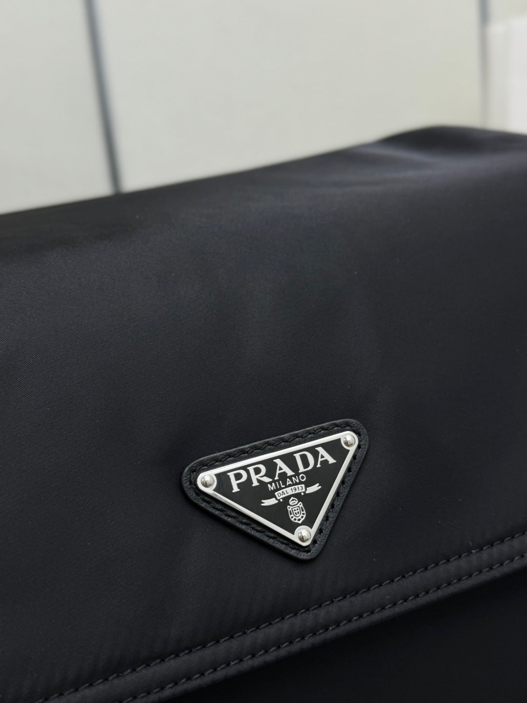 Black Prada logo triangle patch on nylon fabric with stitched trim