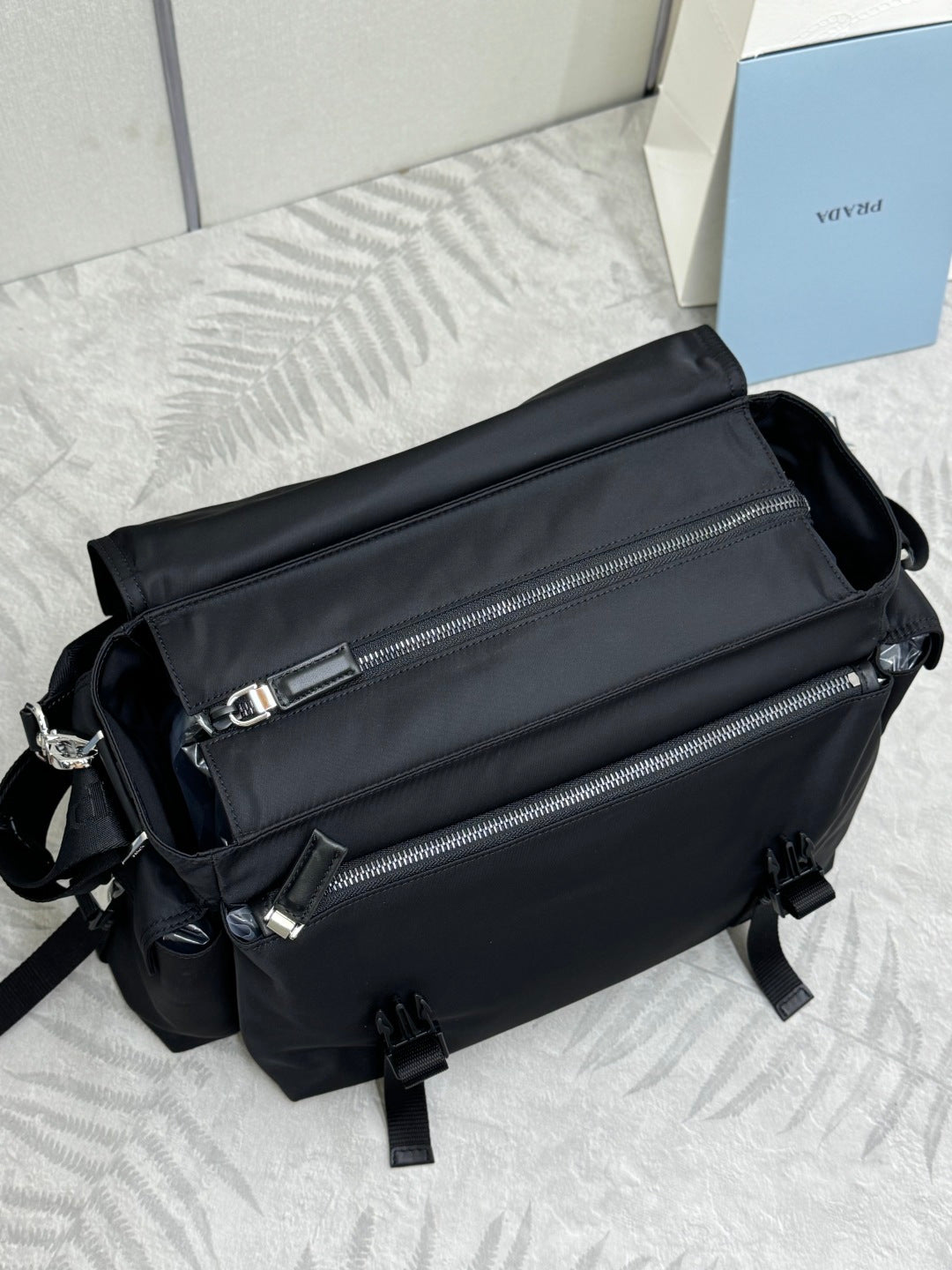 Black Prada nylon sling bag with two front zippers and adjustable shoulder strap