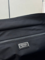 Black Prada nylon bag close-up of silver PRADA logo plate and double zipper