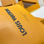 Yellow leather bag with blue 'Louis Vuitton' logo text on textured surface