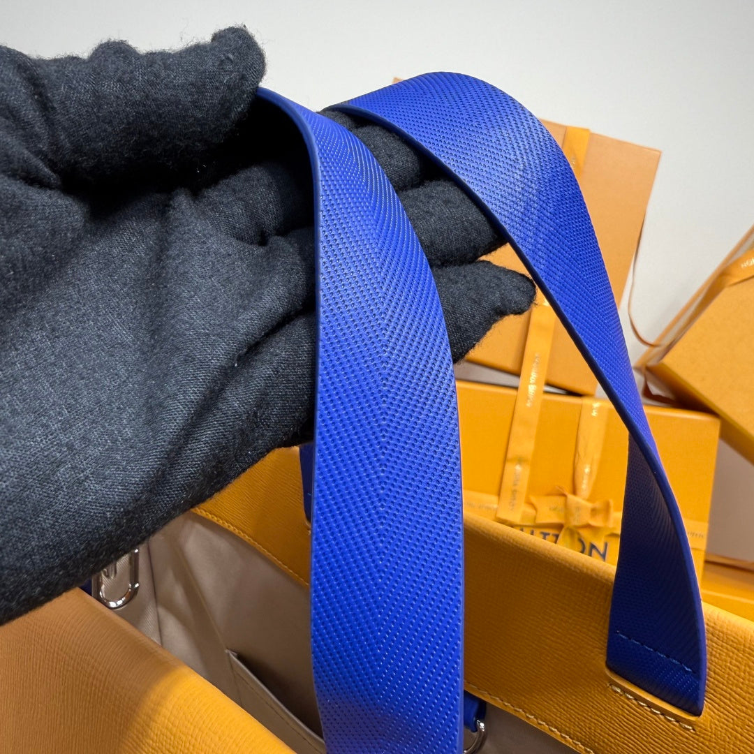Blue woven strap attached to yellow bag with metal clasp and dark fabric grip