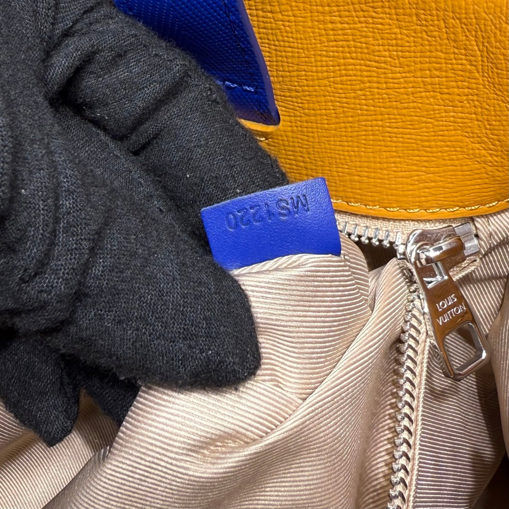 Yellow-and-blue bag closeup: logo patch, striped lining, silver zipper pull