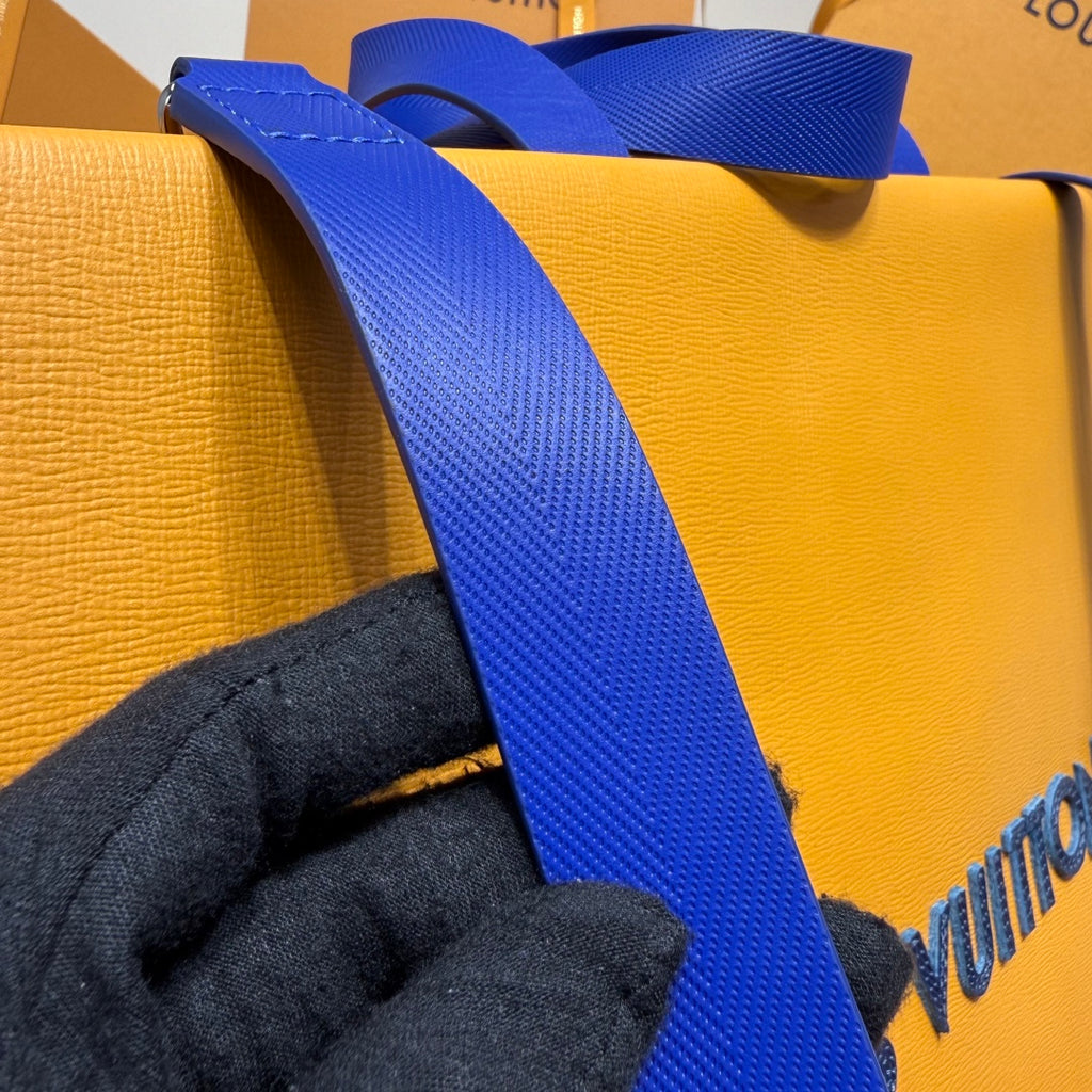Yellow bag with blue webbed strap and stitched seam detail on close-up