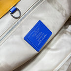Beige fabric bag interior label with blue logo patch and metal zipper detail