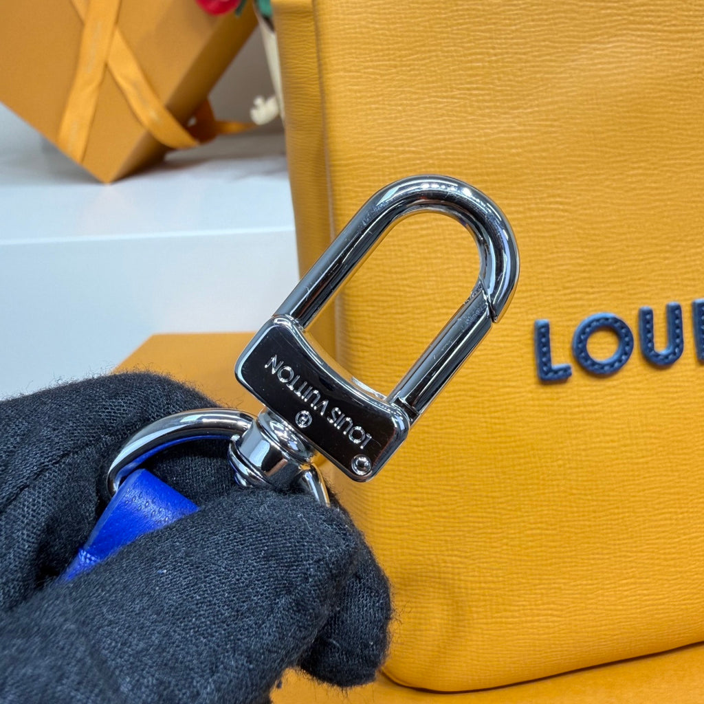Metal D-ring hardware and blue strap on a yellow Louis Vuitton tote bag