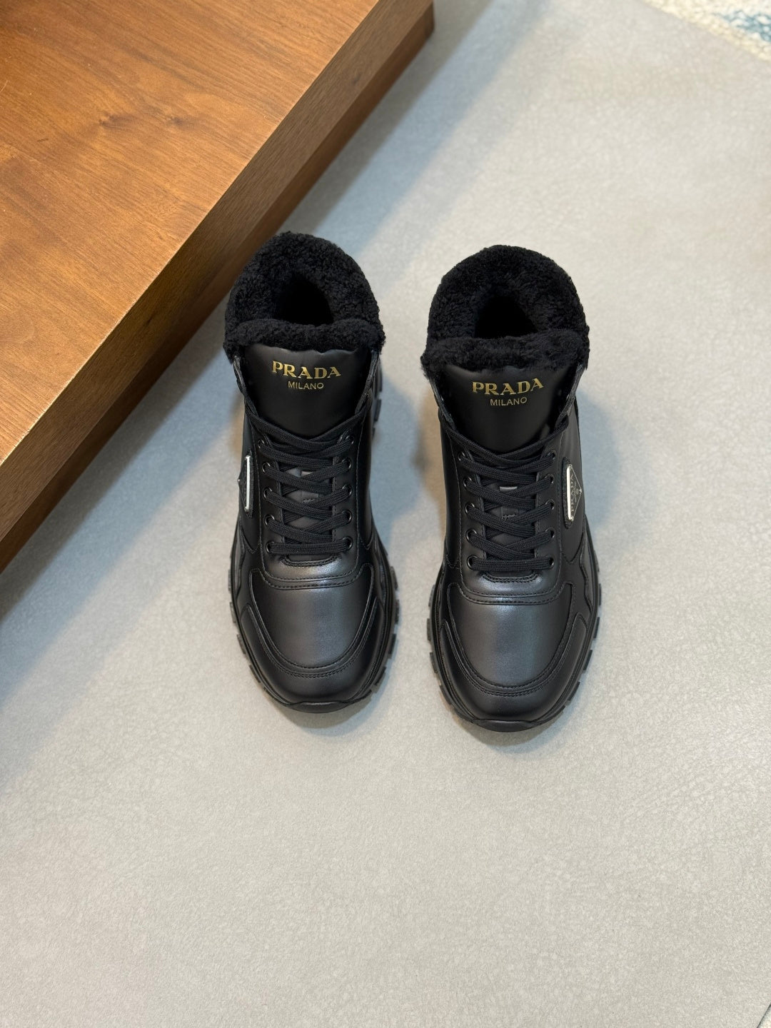 Prada unisex winter sneakers in dark leather with black shearling collar and lace-up front