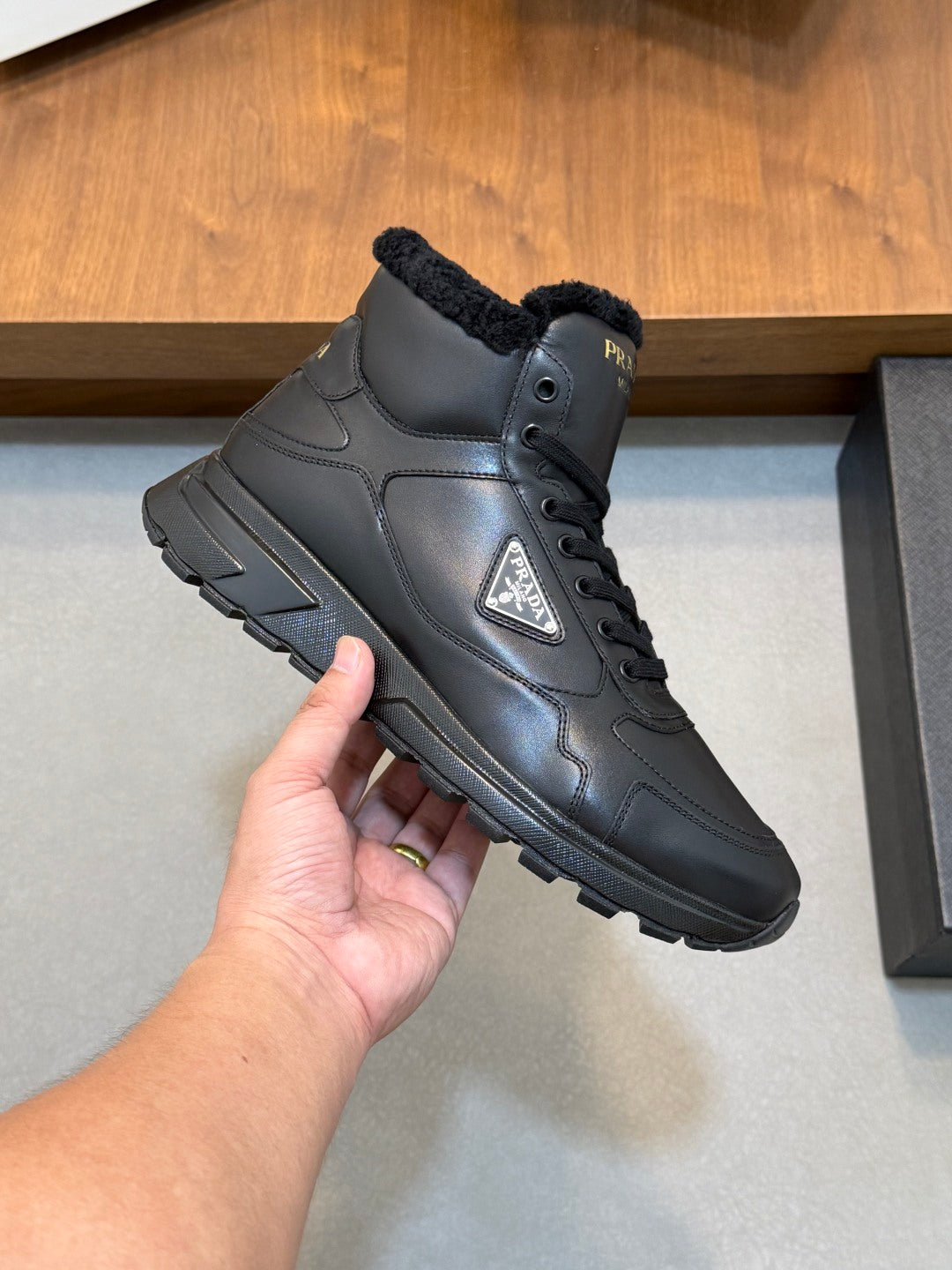 Close-up of Prada dark leather winter sneaker with shearling collar and lace-up eyelets